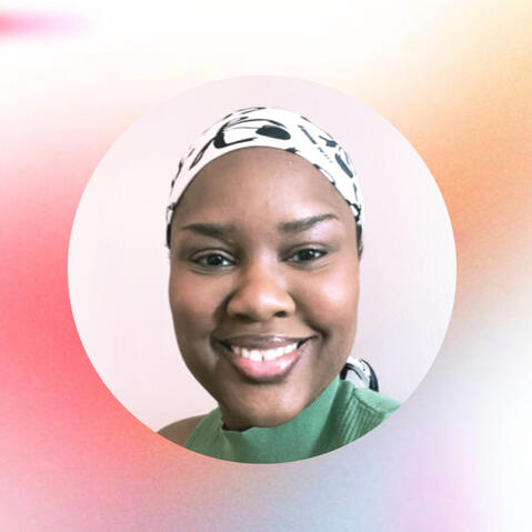 A person in a green shirt and scarf is msiling at the camera.