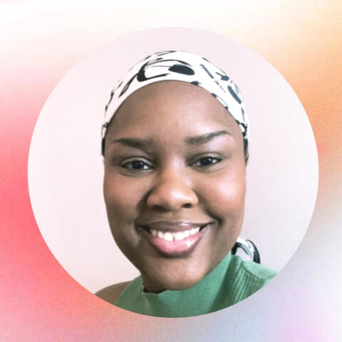 A person in a green shirt and scarf is msiling at the camera.